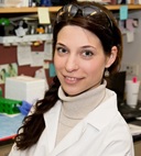 A portrait shot of Galina Semenova in a laboratory, smiling at the camera.