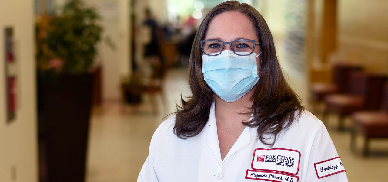 A Fox Chase Cancer Center Clinician, wearing a white coat and mask