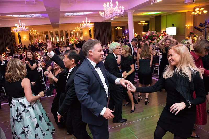 people in fancy attire dancing in a ballroom for In Vino Vita 2022
