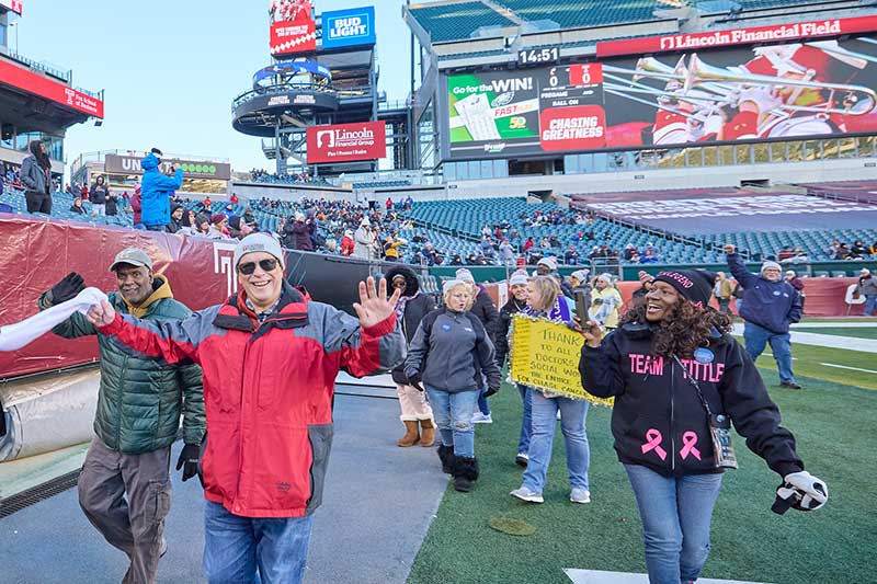 a large group of cancer survivors walking triumphantly through the Lincoln Financial football stadium