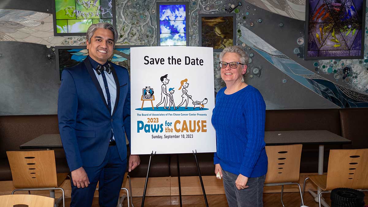 Dr. Abhishek Aphale and Elaine Spangler in front of a Paws for the Cause poster