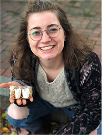 Haley Kravitz smiling, showing an object in the palm of her hand