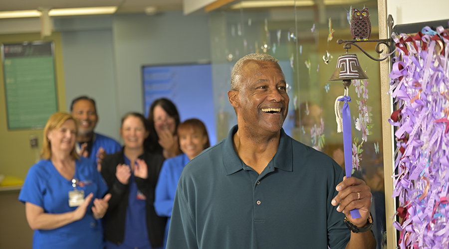 Patient ringing the cancer bell with staff cheering in the back