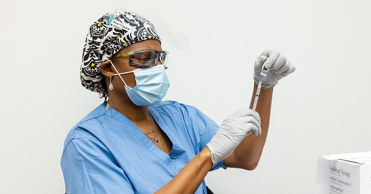 A photograph of a medical professional using a syringe to extract something from a vial.