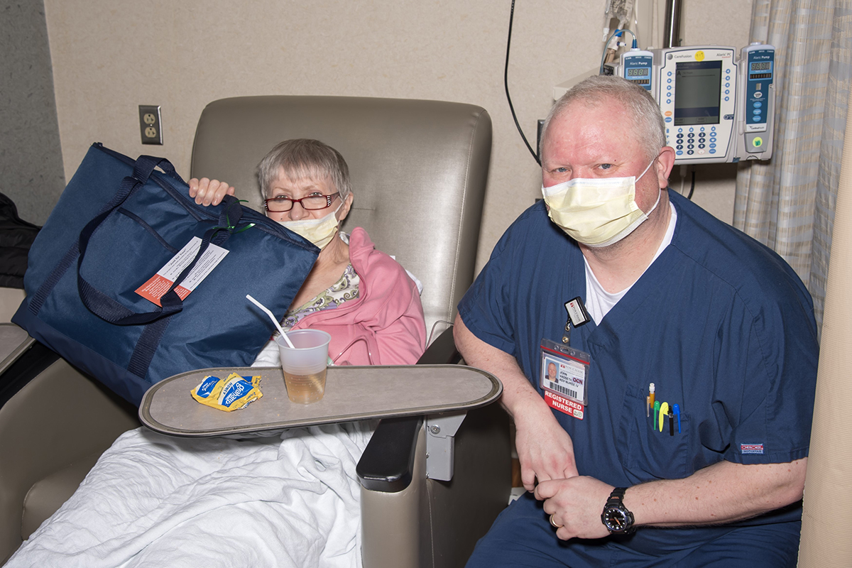 "A chemo patient, next to nurse, holds a bag "