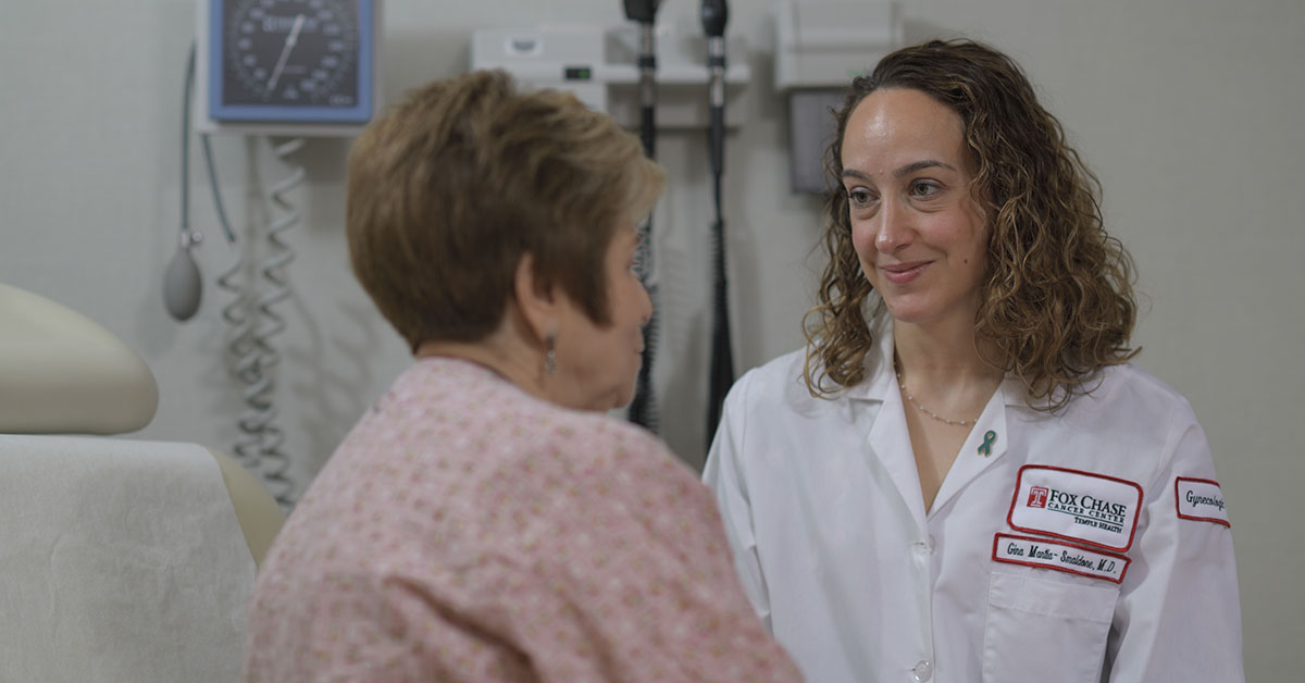 A photo of a Fox Chase doctor smiling at a patient sitting on a medical chair.