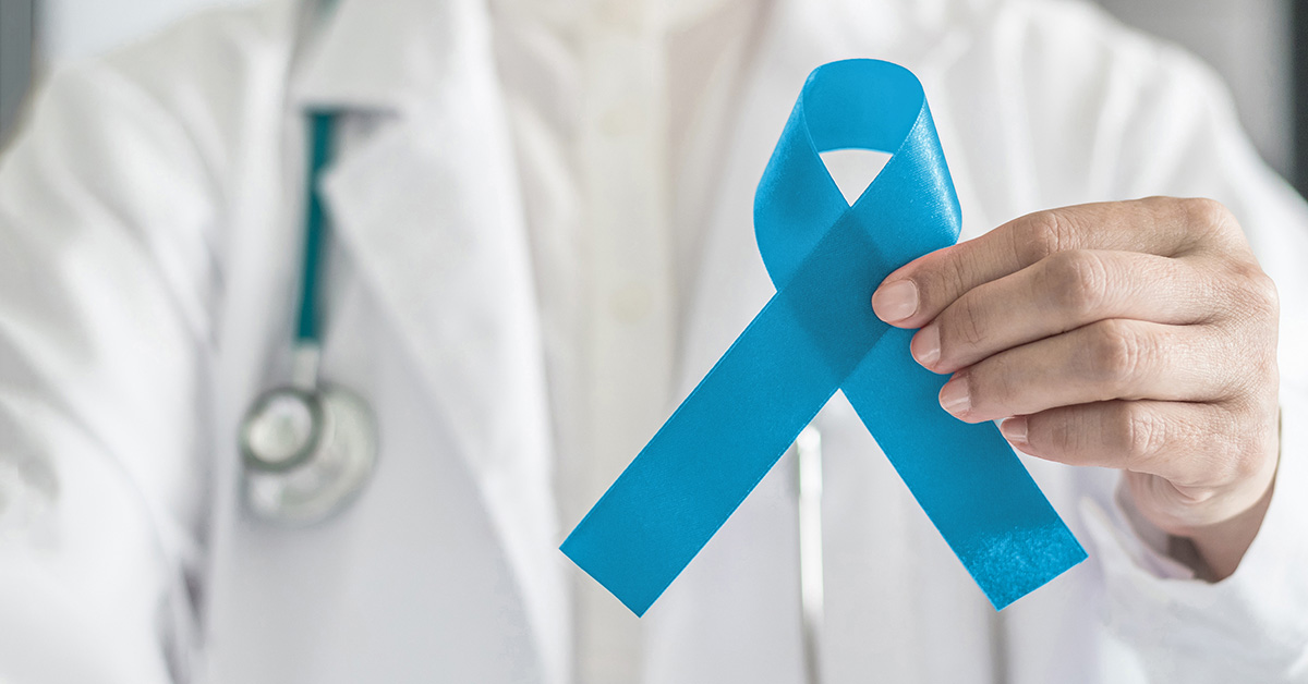 A closeup photo of a medical professional's chest, where they hold a sky blue ribbon in front of them.