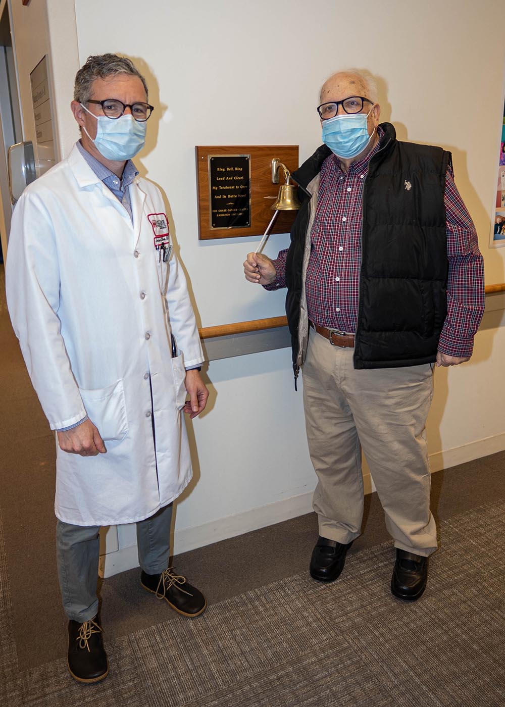 Rodney ringing the bell on his last day of radiation treatment, standing with his radiation oncologist, Dr. Joshua Meyer.