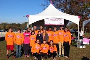 A photograph of a group of teens wearing orange cancer support shirts, standing outside in front of a merchandise tent.