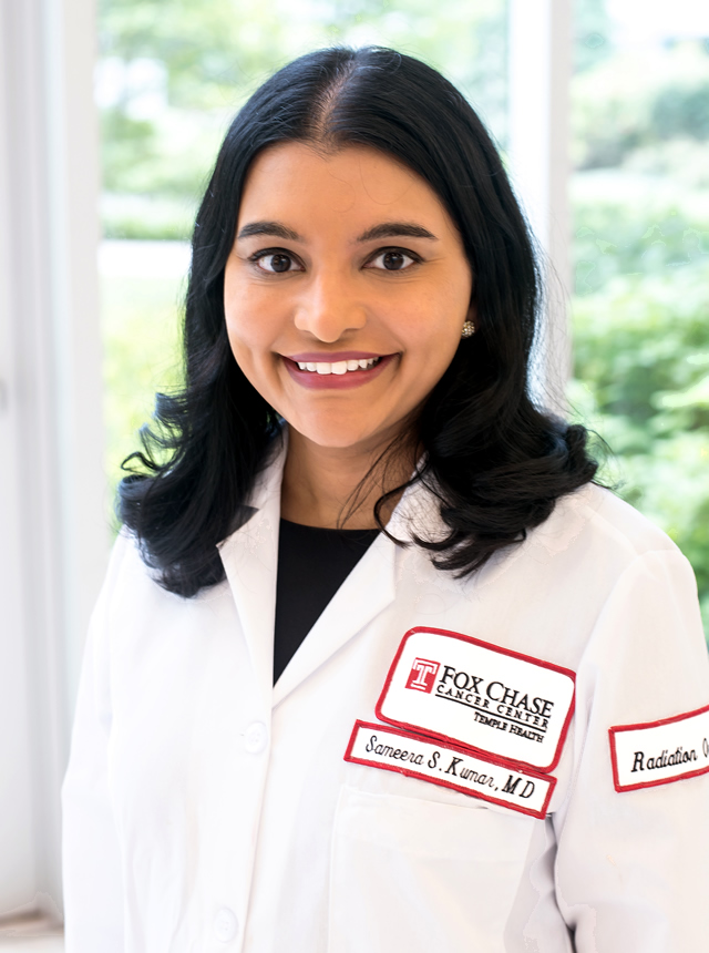 A portrait shot of Dr. Sameera Kumar standing in front of a window.