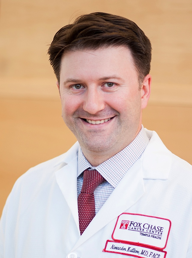 A portrait shot of Dr. Alexander Kutikov, MD, FACS, grinning at the camera.