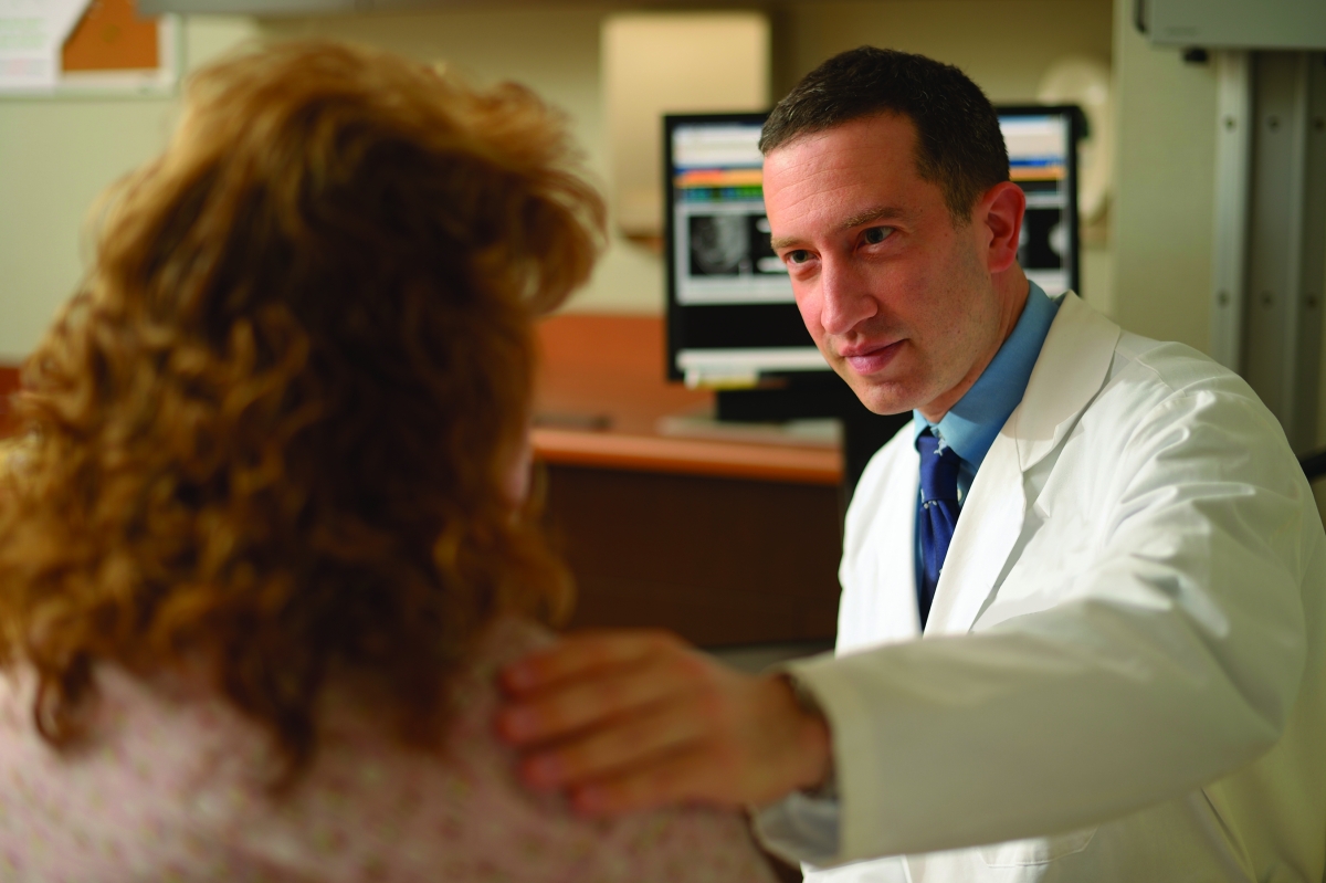 A Fox Chase doctor gently places his hand on a patient's shoulder.