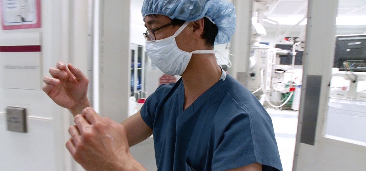 David Chen, an attending surgeon in the Department of Surgical Oncology, scrubs in before performing surgery on a patient with ureteral cancer, using laparoscopic and minimally invasive surgical techniques to reduce the pain, recovery time, and complications.