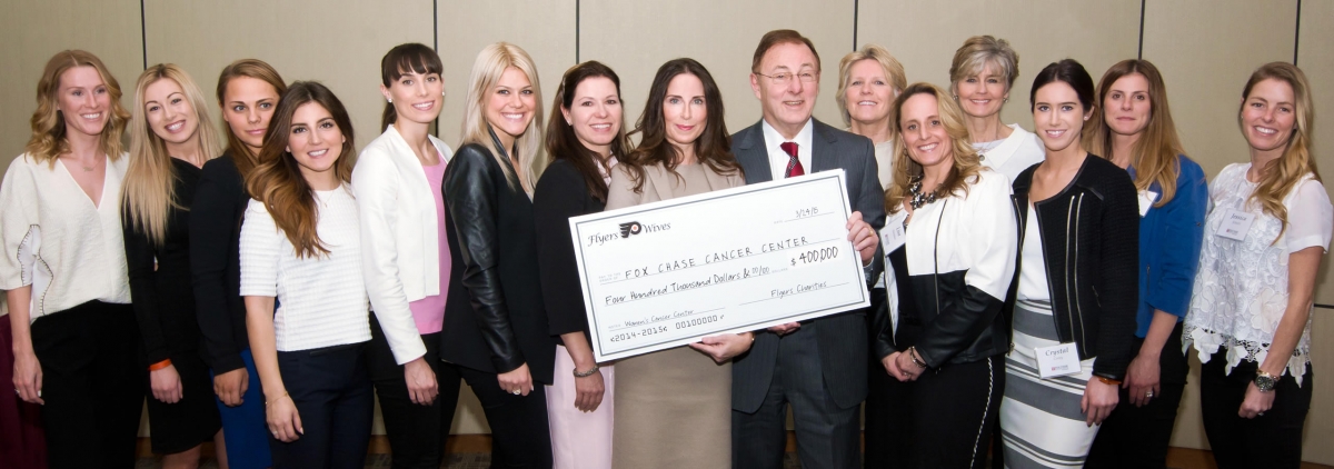 Dr. Fisher is presented with a check by the Flyers Wives.