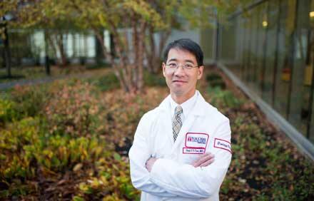 A photograph of a Fox Chase doctor standing outside, crossing their arms and smiling at the camera.