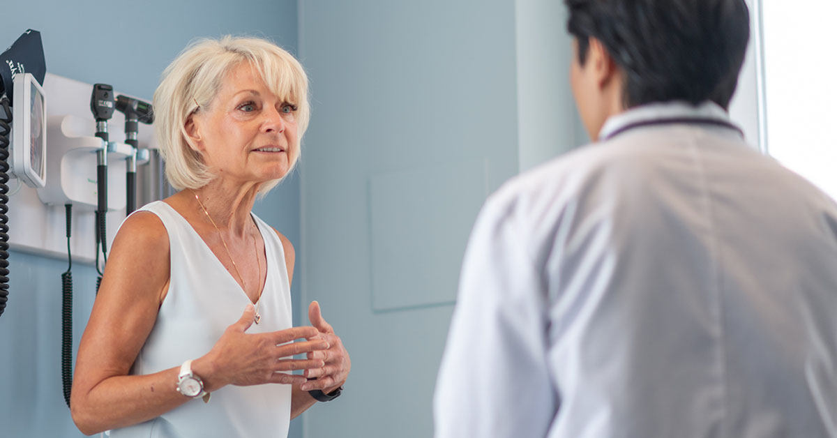 A photograph of two people facing each other in a medical room.