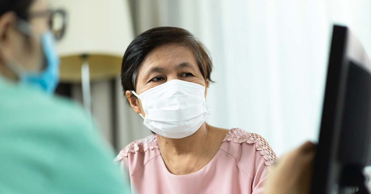 A close up photo of a medical professional and a patient wearing masks and looking at a screen.
