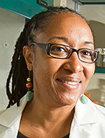 A close up portrait shot of Camille Ragin, smiling at the camera with her head turned slightly to the side.