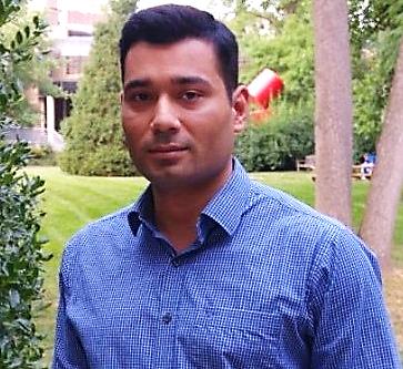 A portrait shot of Vivek Modi standing outside, smiling at the camera.