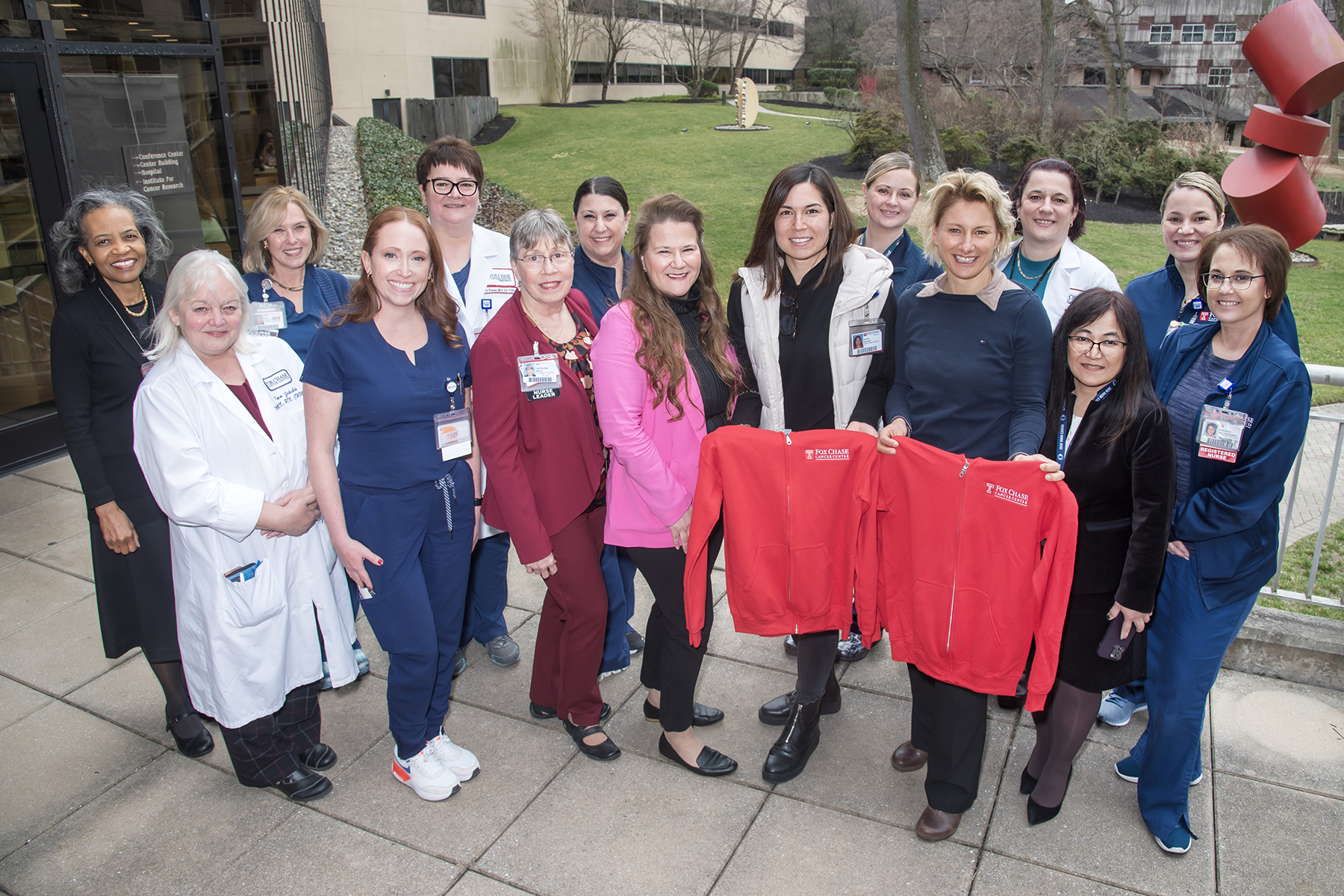 Group of nurses with two nurses holding red Temple sweatshirts in front of them