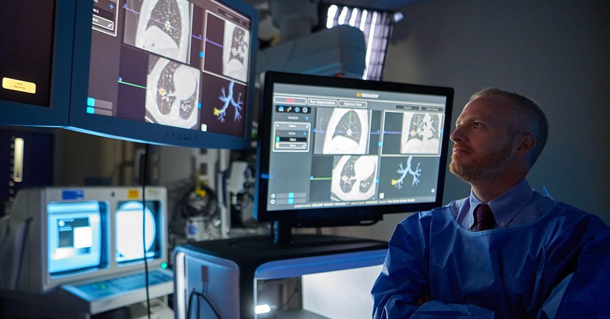 A photo of a medical professional looking at several screens with various medical imaging photos on them.