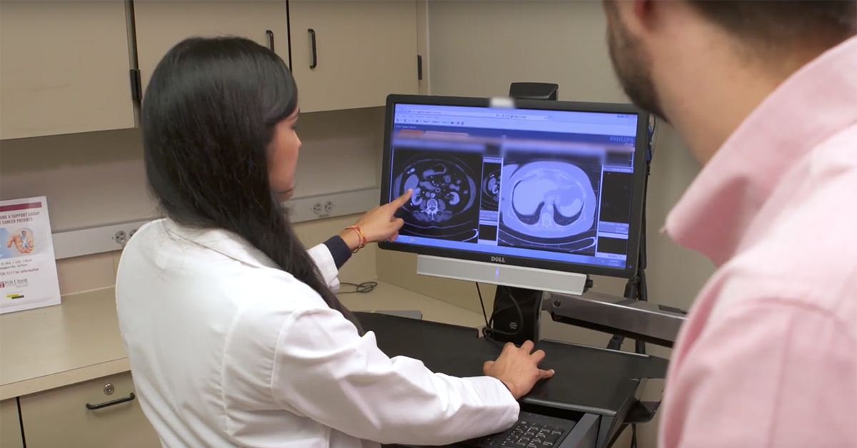 A photograph looking over the shoulders of two people as they look at medical imaging results on a screen.