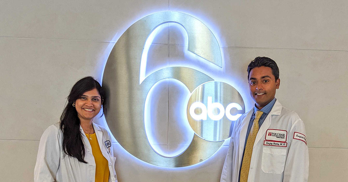 Two Fox Chase doctors stand on either side of a glowing ABC 6 sign.
