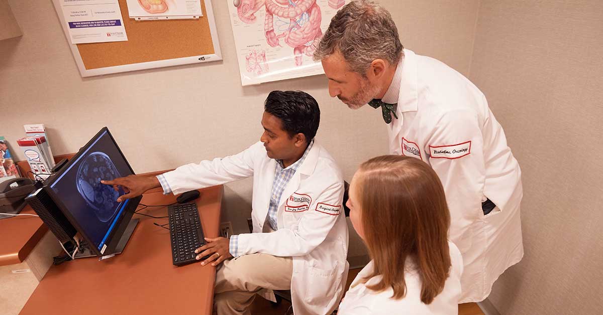 Dr. Sanjay Reddy gestures at a screen as he discusses a particular case with other Fox Chase doctors and specialists.