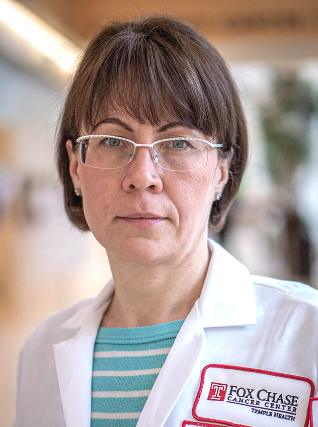 Close-up of Elena Linnik, MSN, FNP-BC, wearing a white coat and glasses