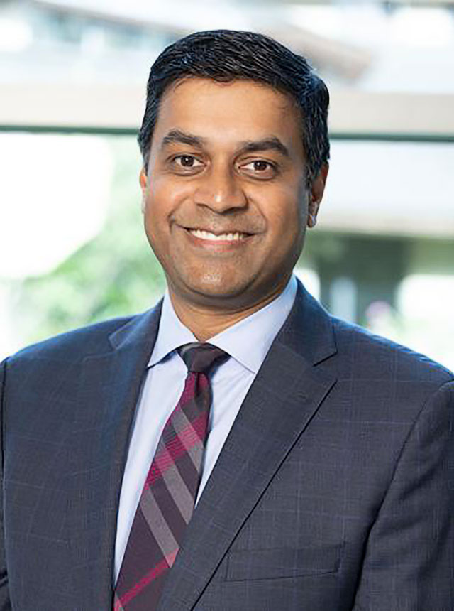 Jay Simhan, a male urologist, wearing a suit and smiling