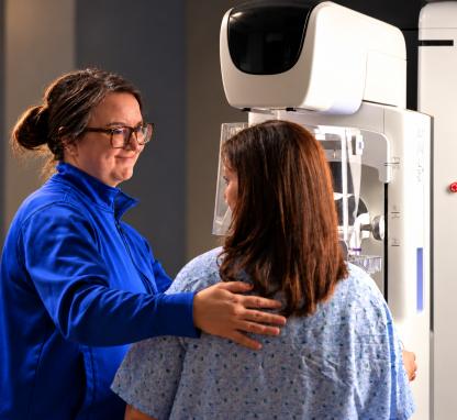 A woman guiding another woman through a mammogram