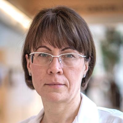 Close-up of Elena Linnik, MSN, FNP-BC, wearing a white coat and glasses