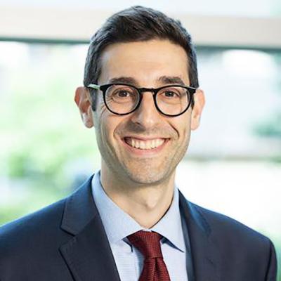 A close-up of Joshua Cohn, a male urologist at Temple Health, wearing glasses and smiling 