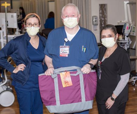Three nurses, one man and two women, with a Chemo comfort bag