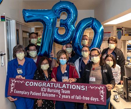 Group of nurses with 730 number balloons and Congratulations sign for 2-year of fall free days.