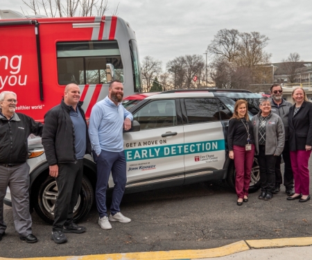 A group of seven people stand beside a Fox Chase Cancer Center–Temple Health vehicle and a large mobile cancer screening bus