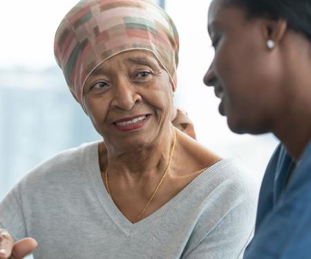 A photograph of two people sitting closely together, smiling and gesturing at a tablet in their hands.
