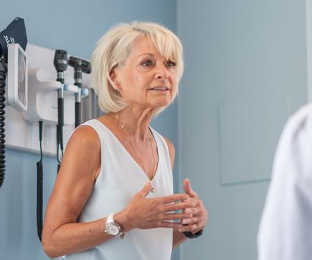 A photograph of two people facing each other in a medical room.