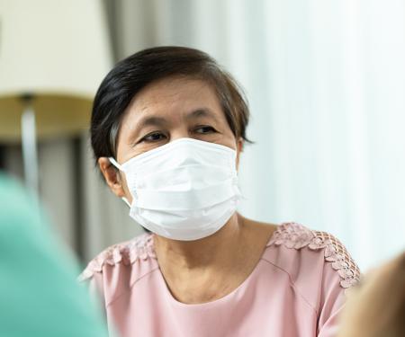 A close up photo of a medical professional and a patient wearing masks and looking at a screen.