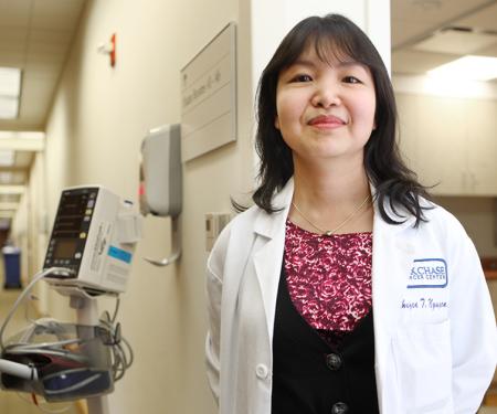 A photo of Dr. Minhhuyen T. Nguyen standing in a doorframe of a hospital hallway, smiling at the camera.