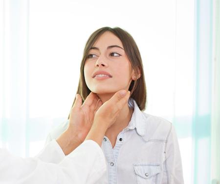 A photograph of a medical professional feeling the sides of a patient's neck.