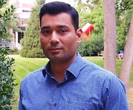 A portrait shot of Vivek Modi standing outside, smiling at the camera.