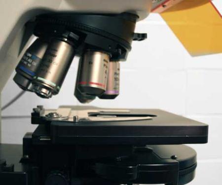 A closeup photo of a microscope with various focusing lenses.
