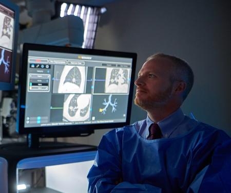 A photo of a medical professional looking at several screens with various medical imaging photos on them.