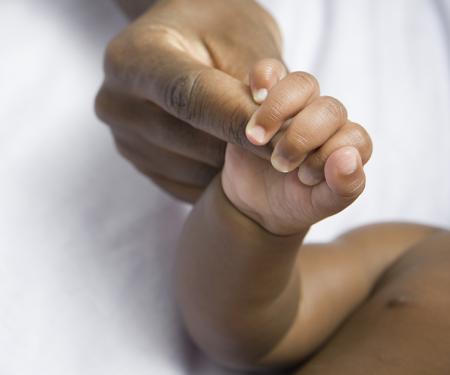 A closeup photo focused on the hand of a baby clutching a person's finger tightly.