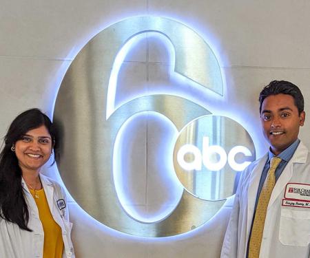 Two Fox Chase doctors stand on either side of a glowing ABC 6 sign.