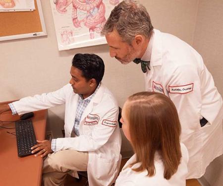 Dr. Sanjay Reddy gestures at a screen as he discusses a particular case with other Fox Chase doctors and specialists.