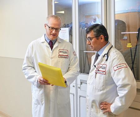 A photograph of two Fox Chase doctors standing in a hallway and looking at a file together.