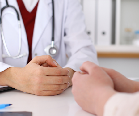 Clinician discussing procedures with a potential patient, wearing a lab coat