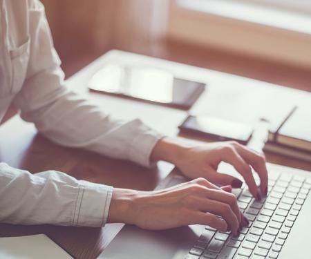 A photo with heavy post processing of a person sitting at a desk using a laptop.
